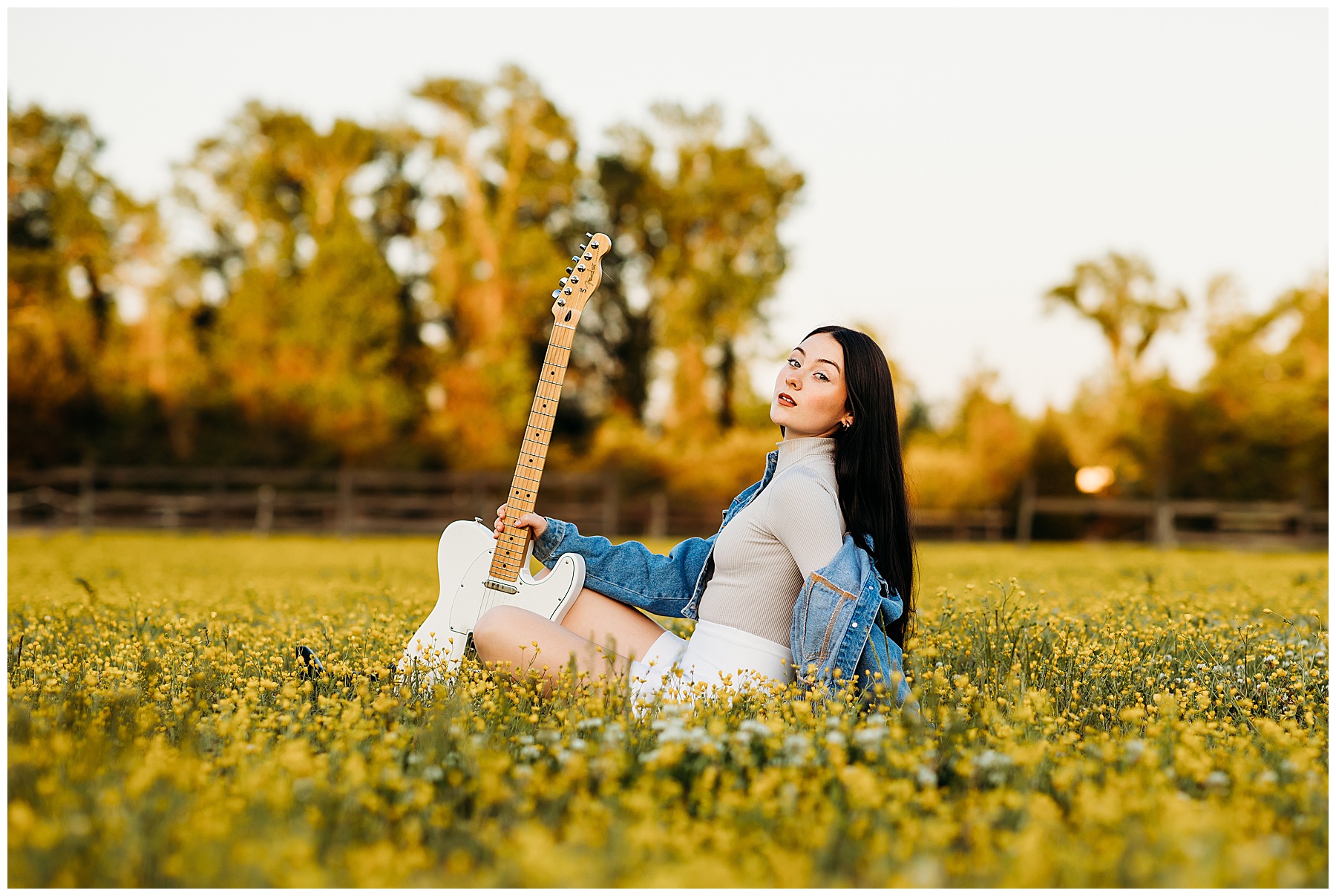 Girl posing with her guitar in a field of yellow flowers.