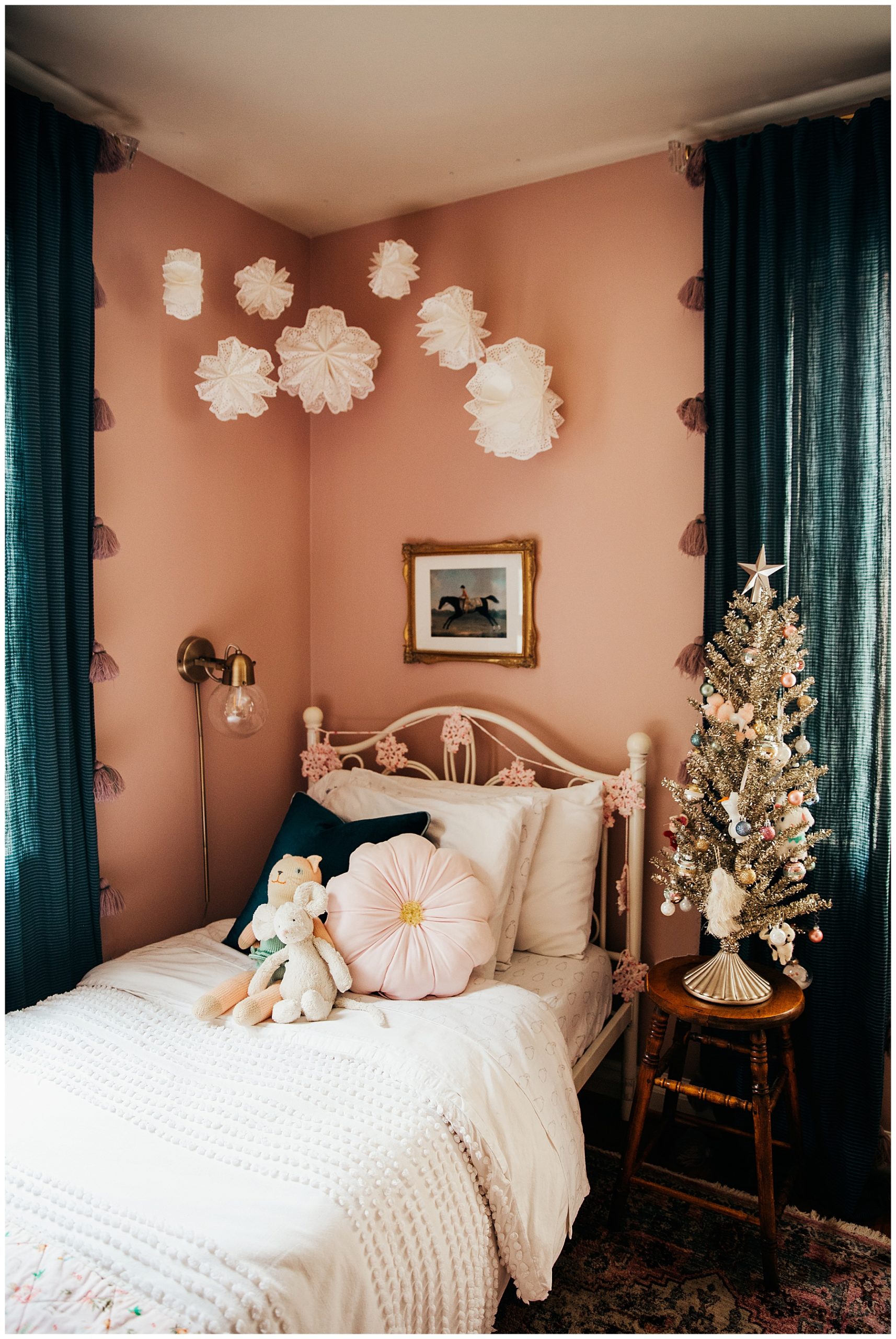 Girls twin bed decorated for Christmas with paper doilies snowflakes hanging above.